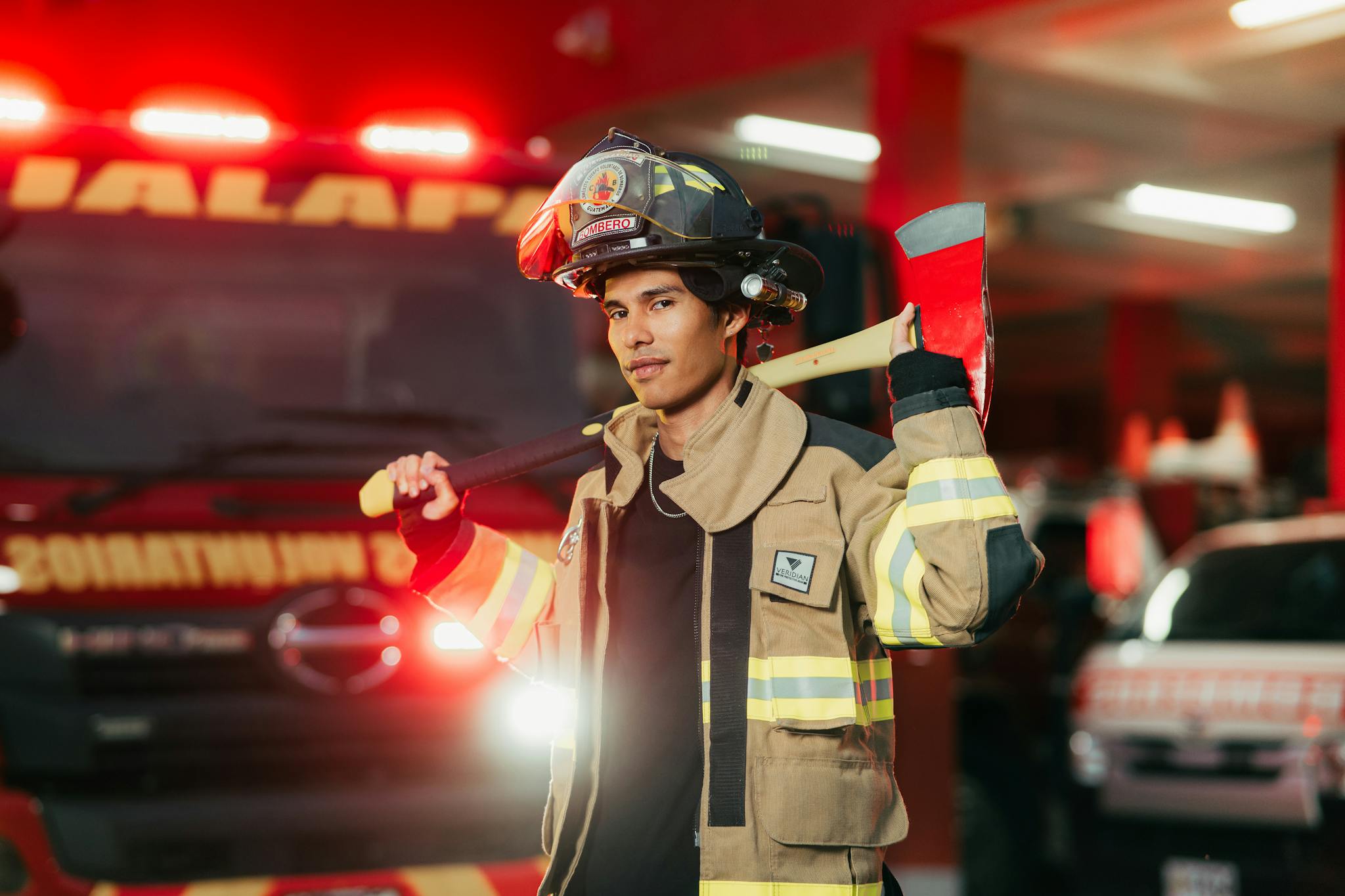 Firefighter posing confidently with an axe at a fire station in Ciudad de Guatemala.